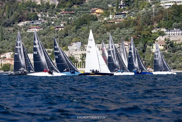 Flota klasy 5.5 Metre płynąca blisko brzegu w Malcesine nad jeziorem Garda