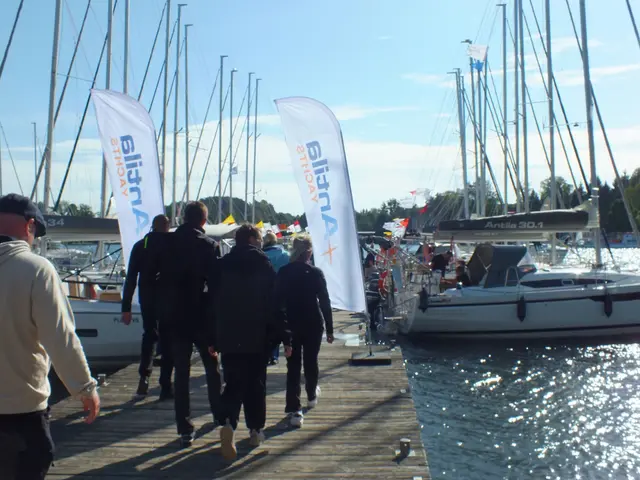 Żeglarze idą pomostem między jachtami i flagami Antila Yachts