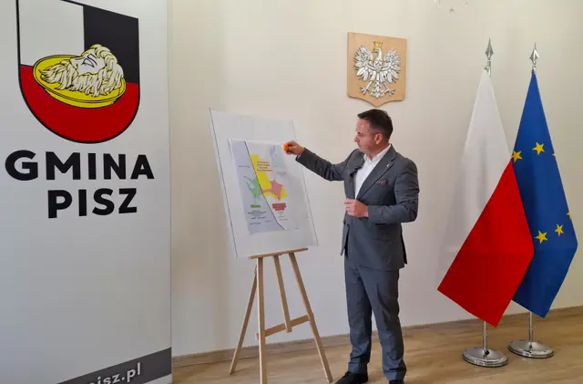 Burmistrz Pisza Dariusz Kiński omawia mapę własności działki nad Śniardwami podczas konferencji prasowej