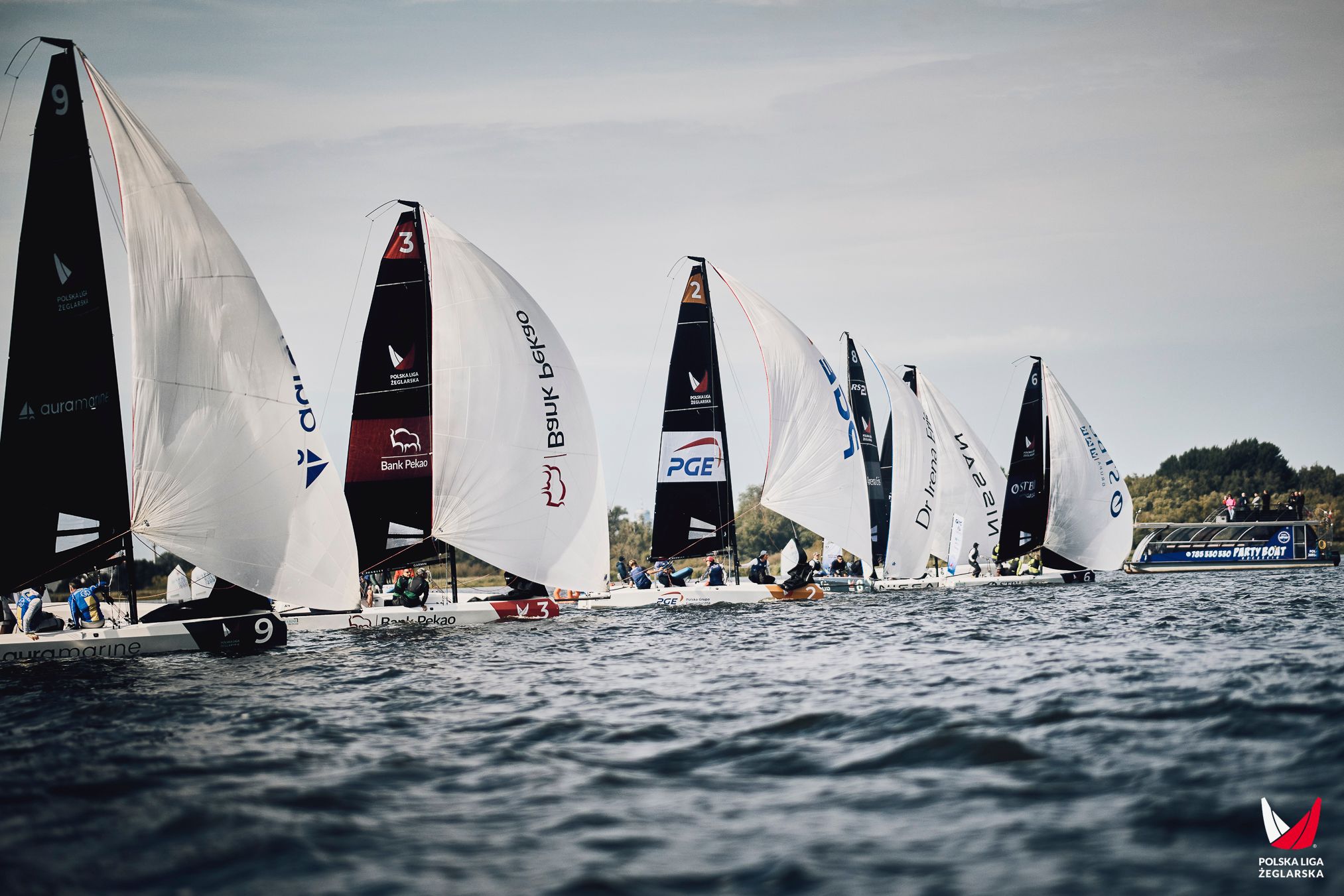 Grupa jachtów klasy RS21 płynąca w szyku podczas regat ligowych