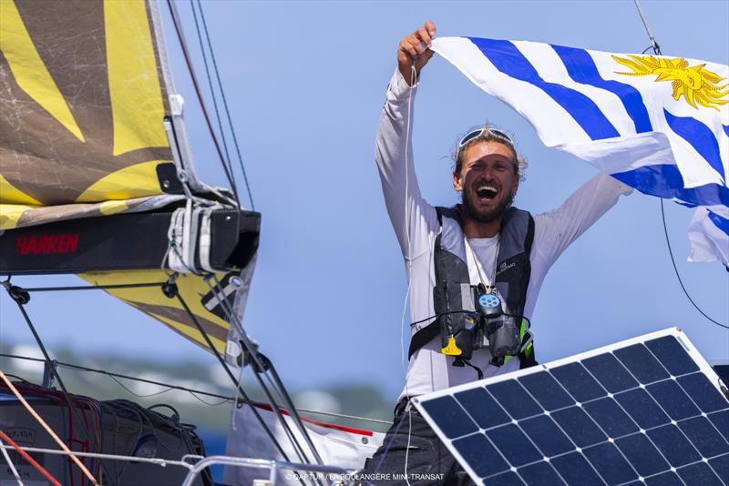 Uśmiechnięty Federico Waksman unosi flagę Urugwaju na pokładzie jachtu z panelem słonecznym