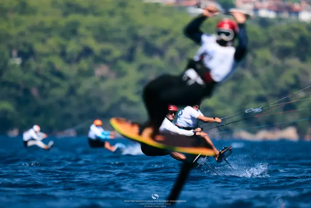 Zawodnik Formula Kite w zwrocie na foilu, za nim czerwony latawiec