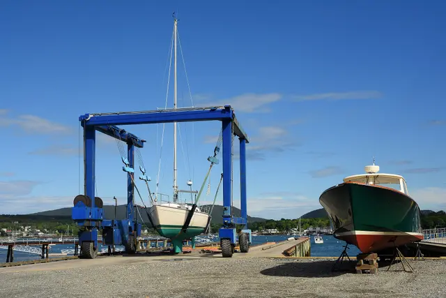 Jacht żaglowy podniesiony na pasach bramownicy w marinie