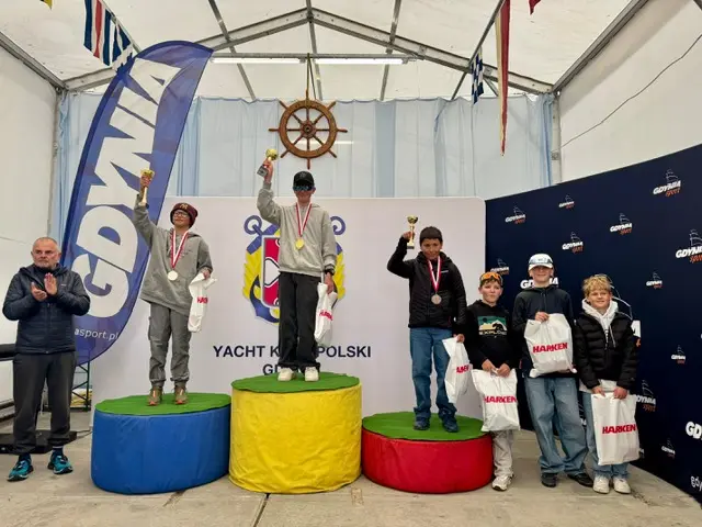 Młodzi żeglarze klasy Optimist z pucharami i medalami na podium Jesiennego Pucharu Gdyni