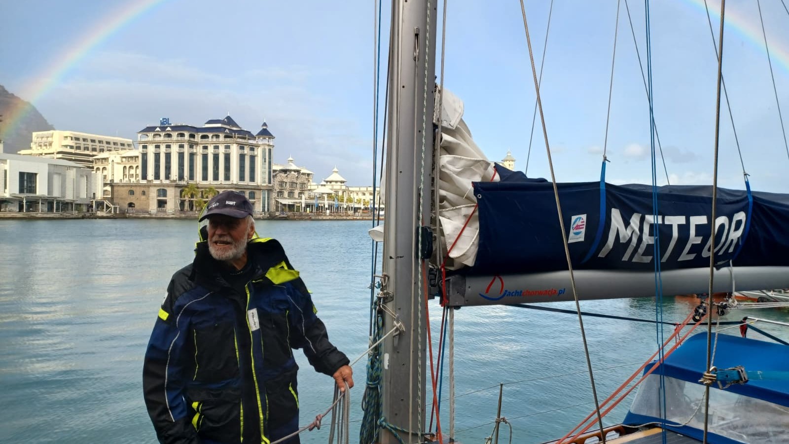 Kapitan Krzysztof Baranowski w sztormiaku stoi przy maszcie jachtu METEOR w marinie Le Caudan w Port Louis
