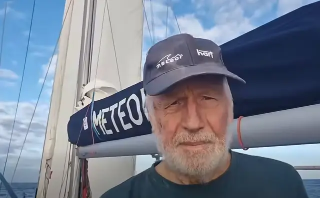 Kapitan Krzysztof Baranowski w czapce z logo Meteor i Hart na tle bomu jachtu METEOR