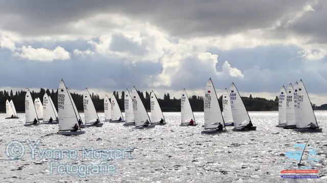 Flota łódek OK Dinghy na kursie ostrym pod zachmurzonym niebem w Bruinisse