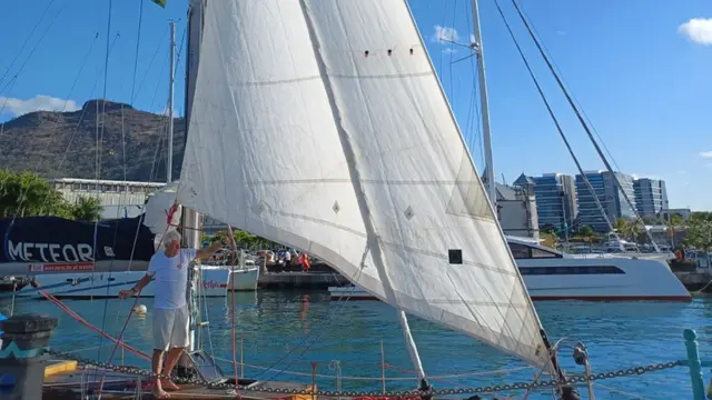 Żeglarz na dziobie jachtu Meteor przy postawionym żaglu przednim w marinie Port Louis