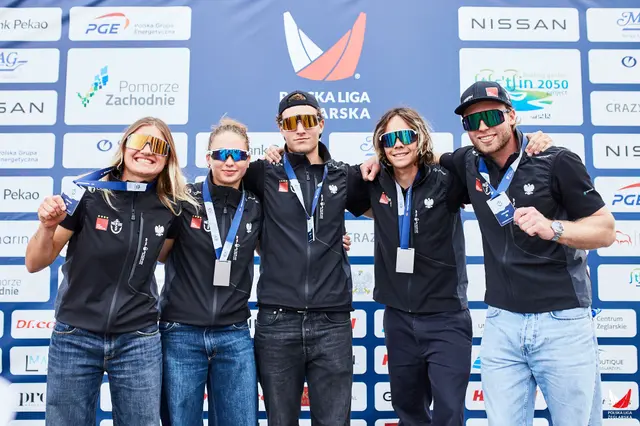 Pięcioro żeglarzy z medalami na tle ścianki Polskiej Ligi Żeglarskiej w Szczecinie