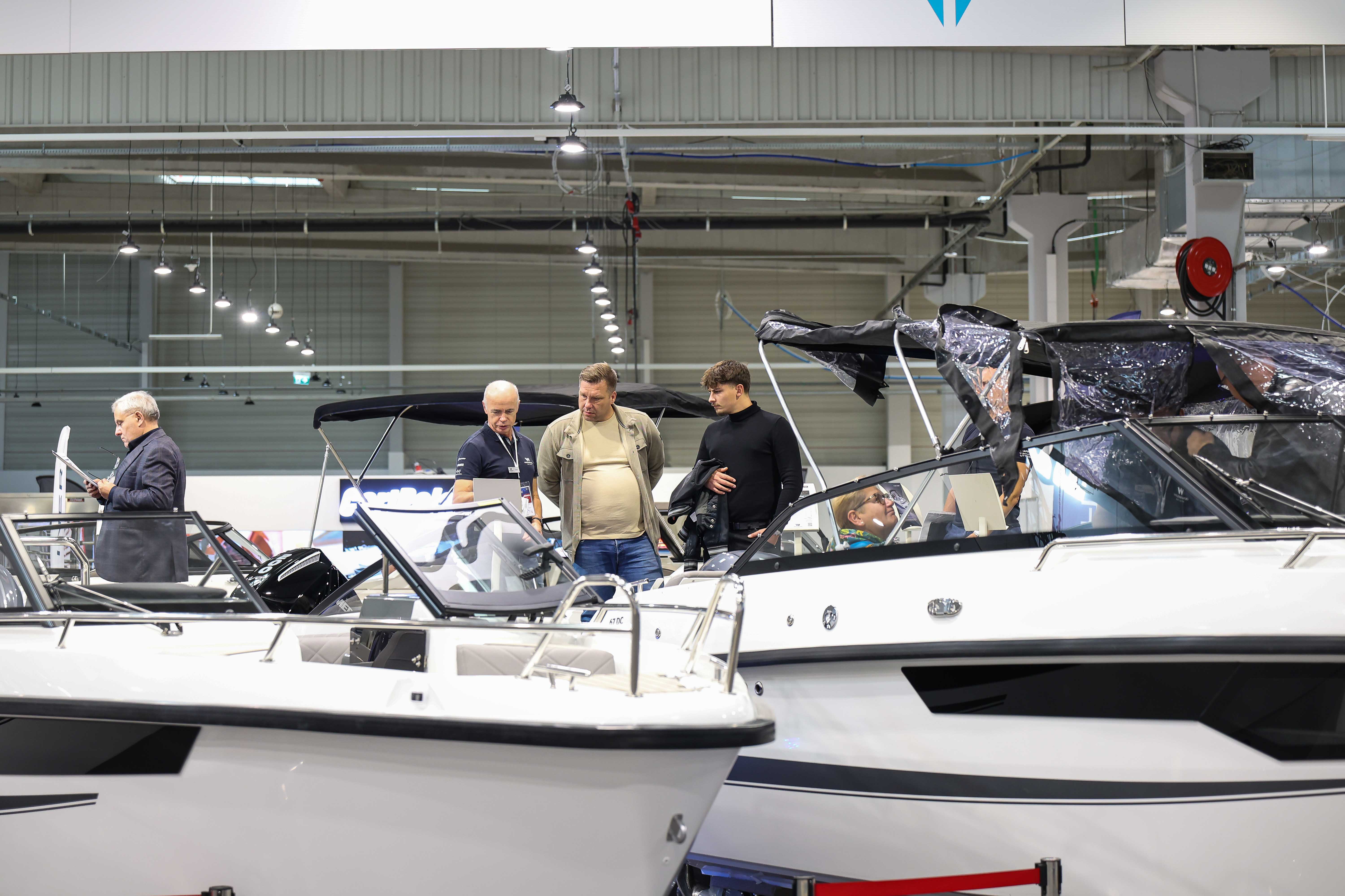 Odwiedzający i sprzedawcy przy białych motorówkach na Poland Boat Show