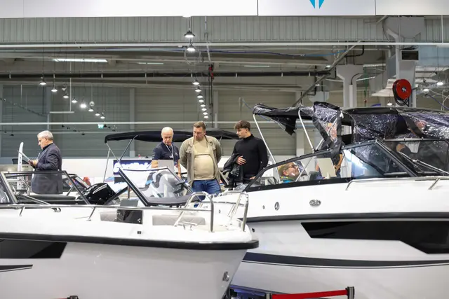 Odwiedzający i sprzedawcy przy białych motorówkach na Poland Boat Show