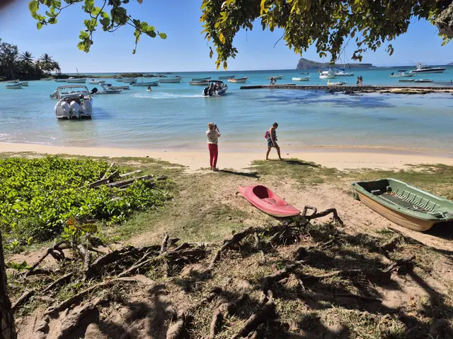 Plaża i łodzie na turkusowej wodzie zatoki na północy Mauritiusa, w oddali skalista wysepka