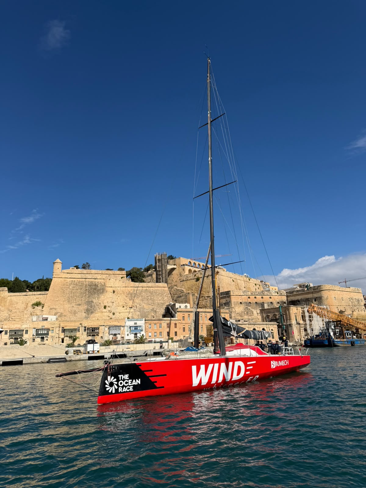 Czerwony Volvo Ocean 65 Wind Whisper na wodzie Grand Harbour pod murami Birgu